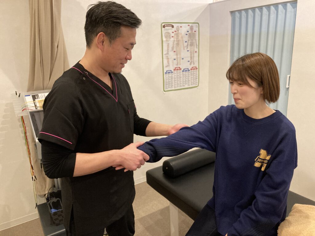 松戸市串崎新田のあき接骨院院長の筒井豪（つついたくま）がばね指の痛みで悩んでいる方に対し施術を行っている写真
